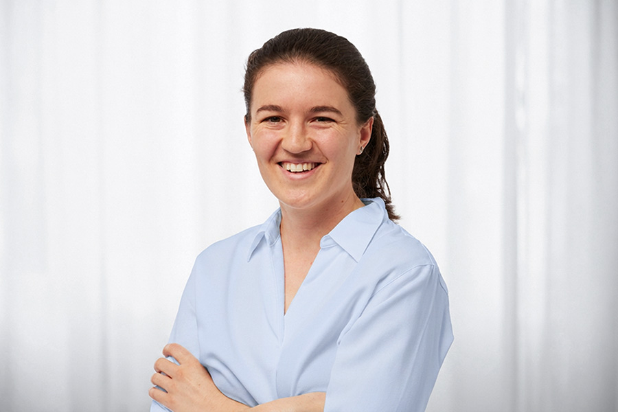 Smiling woman in a pale blue blouse, head and shoulders against a white background.