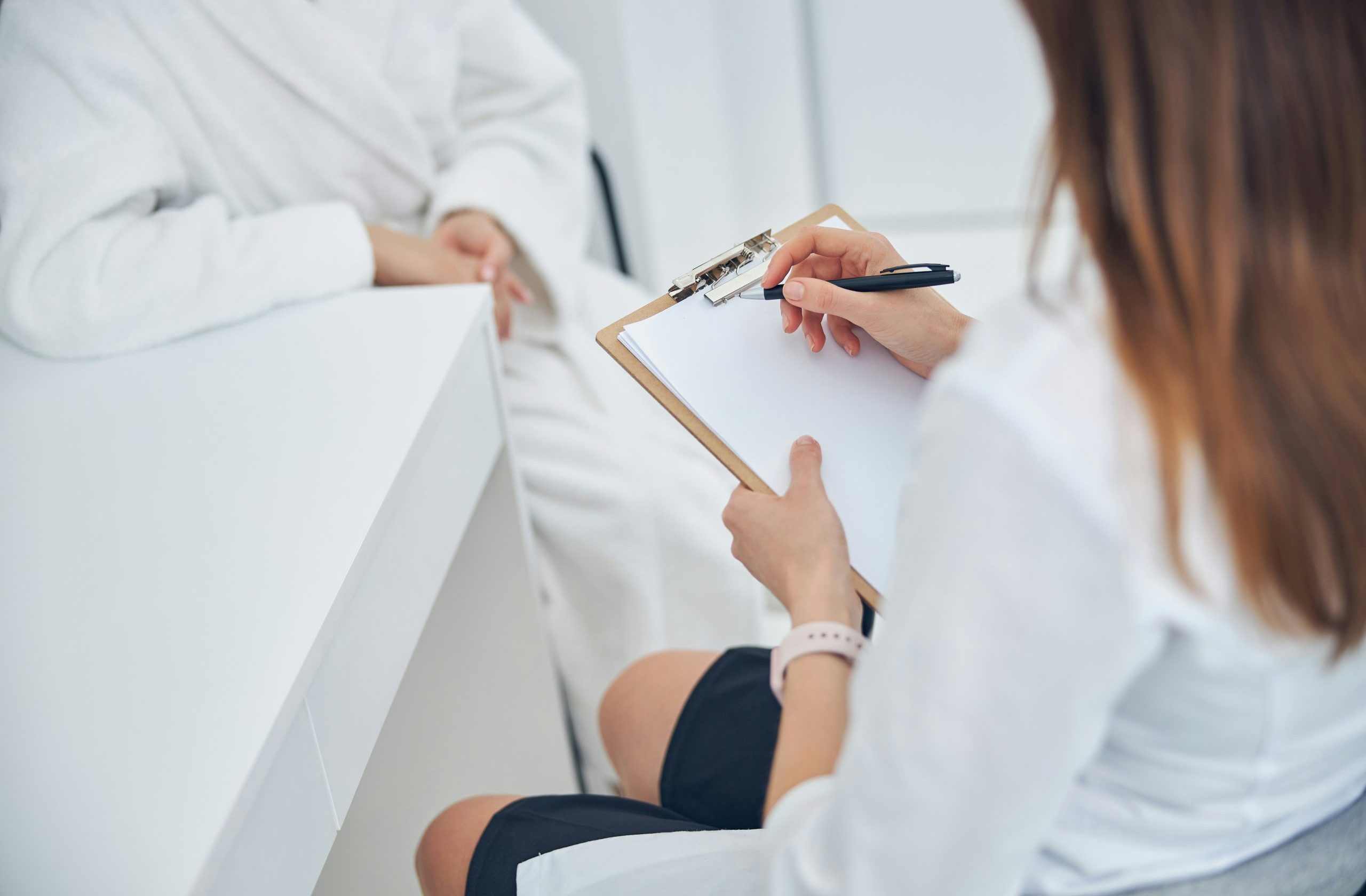 Naturheilkundliche Beratung: Therapeutin notiert Behandlungsplan der Patientin